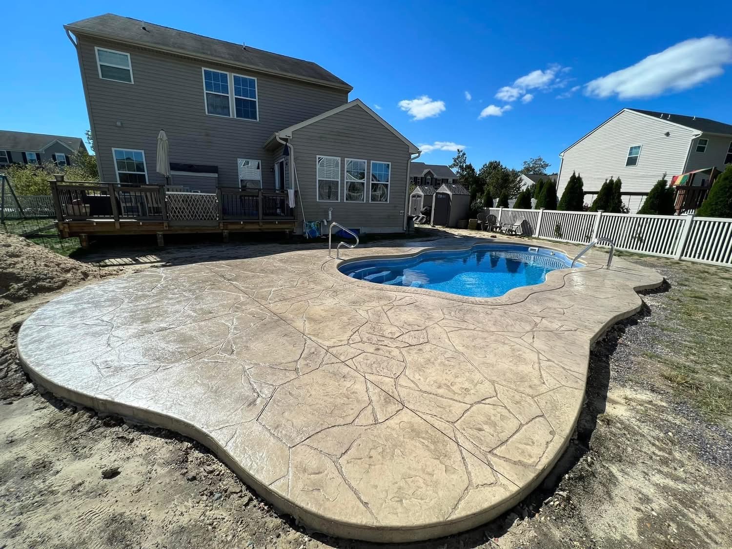 Stamped concrete pool deck surrounding a backyard swimming pool